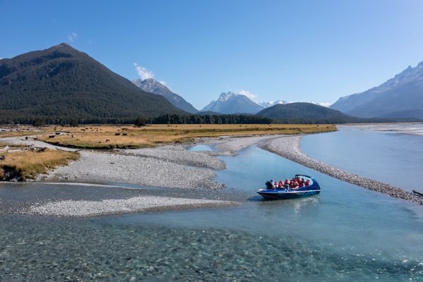 Dart River Adventures jet boat on the Dart River with scenic views of mountains behind